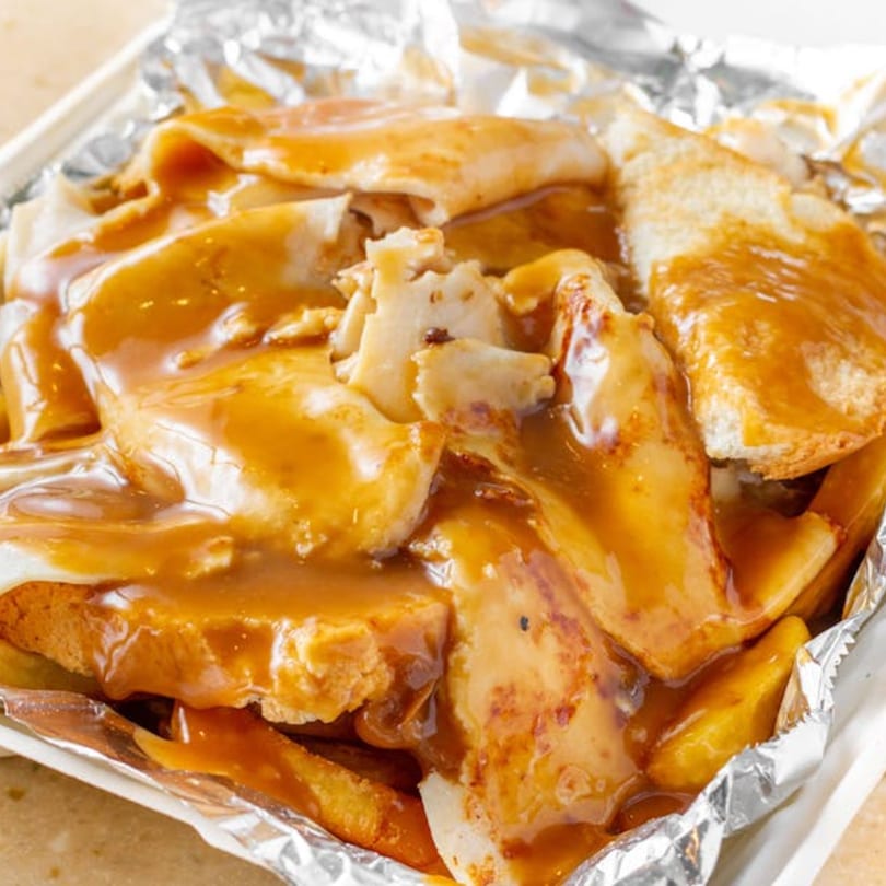 Bellagio Wings & Pizza's hot chicken sandwich with gravy and fries in a foil-lined container.