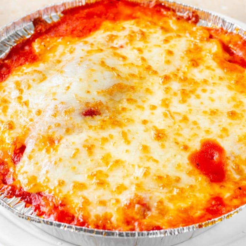 Baked lasagna with melted cheese and red sauce in a foil container from Bellagio Wings & Pizza.